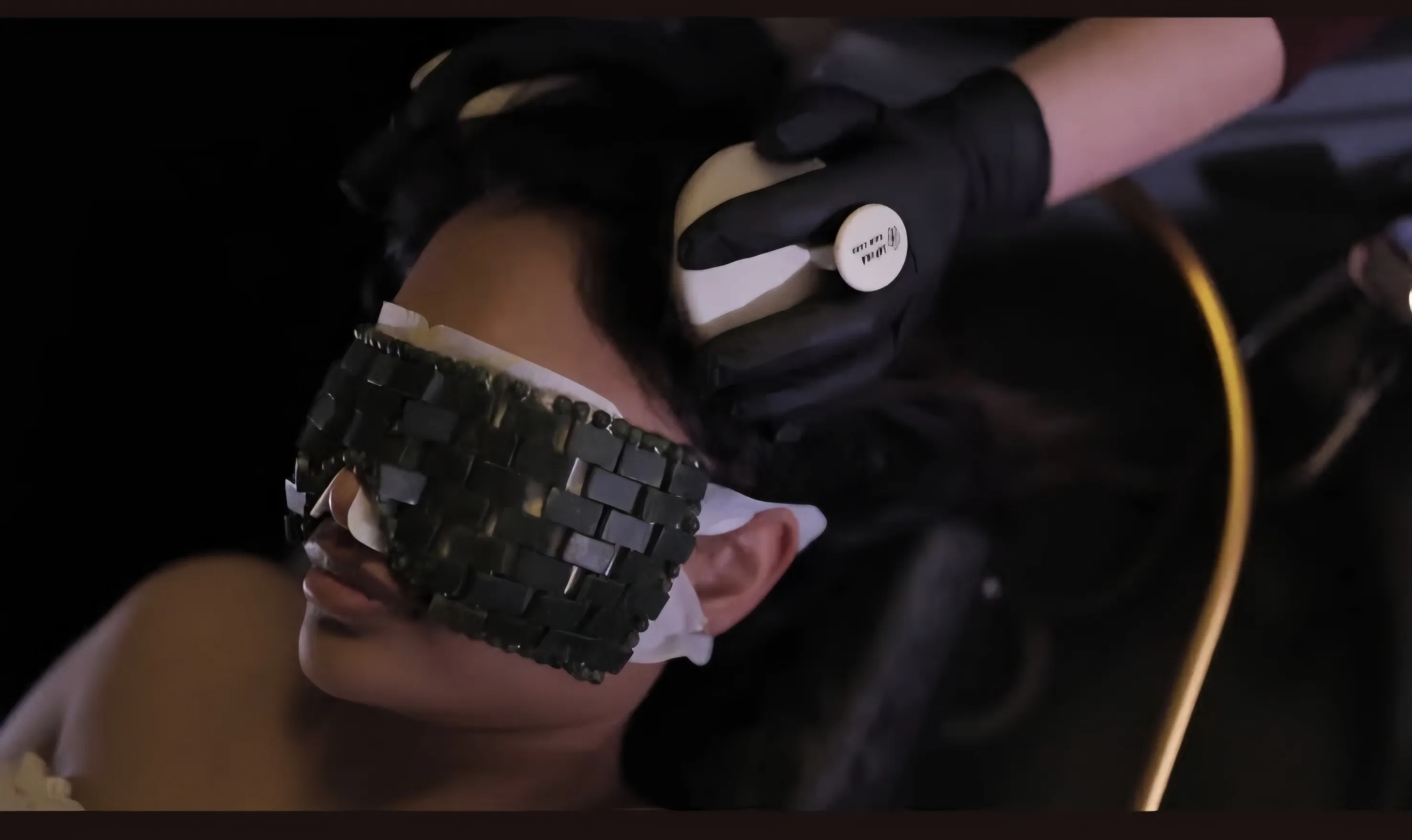 A woven dark-stone eye mask resting over a guest's eyes during a Miyabi treatment