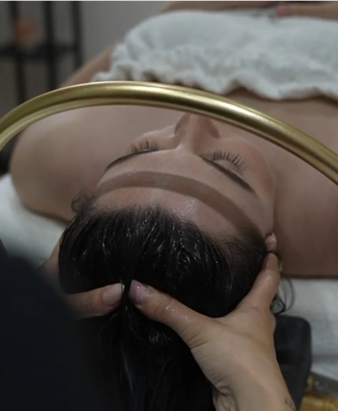 The signature Halo — a gold ring of light arcs over a reclining guest during the Miyabi scalp ritual